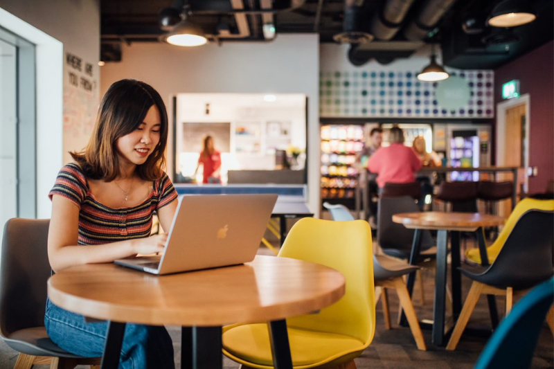 female graduate sitting on laptop in a cafe