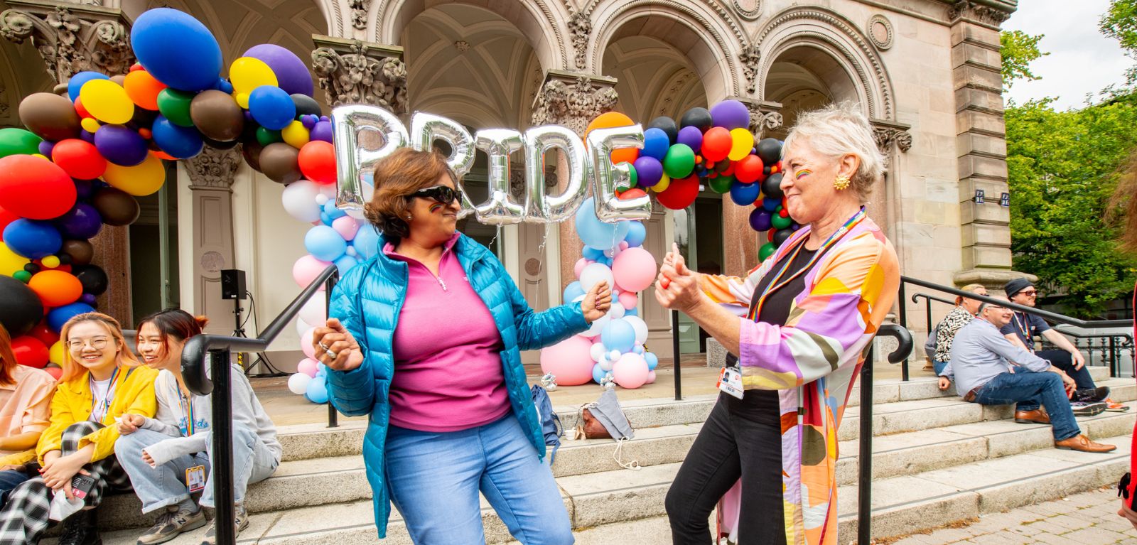 Two women dancing at the Pride Picnic in front of the Elmwood Hall