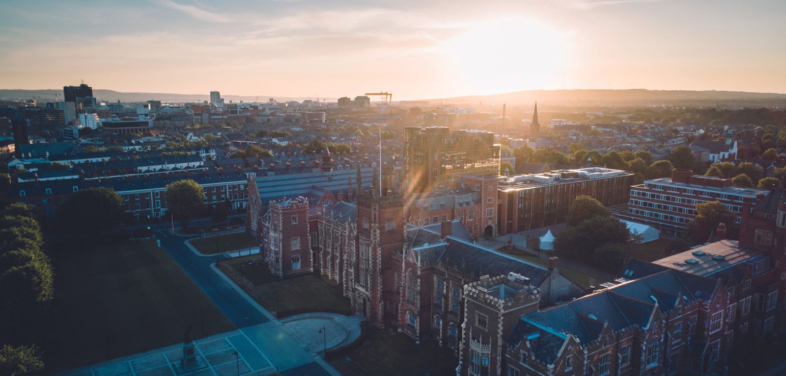 Sun rising over the red-bricked Lanyon building against the Belfast skyline