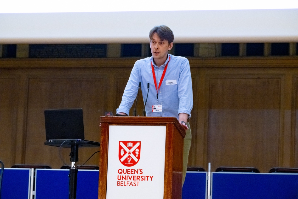 postdoc presenting on stage at Queen's Postdoc Showcase 2023 in the Whitla Hall