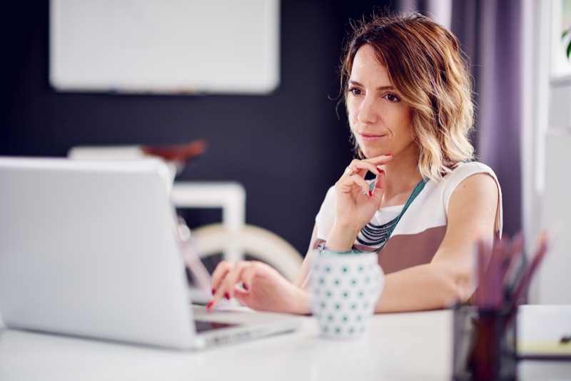 woman working on a laptop whilst sitting at a table