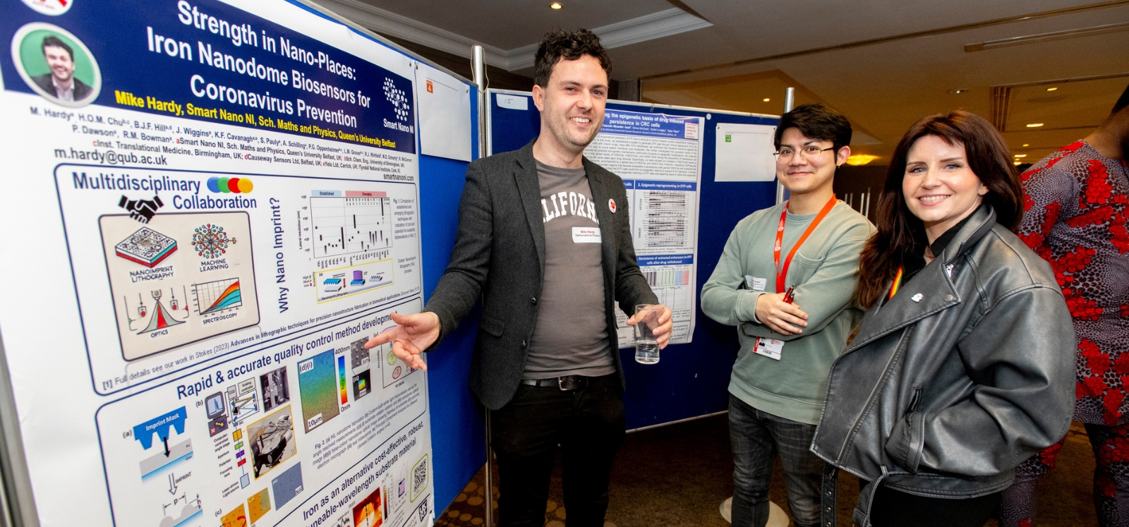 three smiling postdoctoral researchers chatting about a research poster at the Postdoc Showcase 2024, Queen's University Belfast