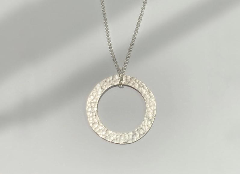 a handmade silver ring necklace on a display cloth